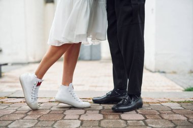 Ayakların yere yakın görüntüsünü al. Nişanlısıyla güzel gelin dışarıda evleniyor..