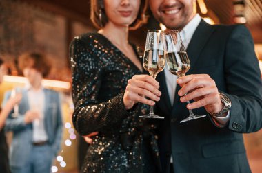 Çift poz veriyor. Güzel giyinmiş bir grup insan içeride yeni yılı kutluyorlar..