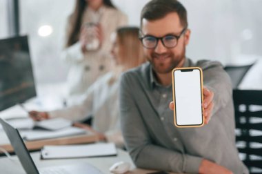 Akıllı telefonun yakın görüntüsü. Uzayı kopyala Ofiste başarılı bir ekip birlikte çalışıyor. İş kavramı.