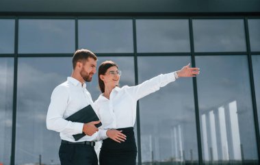 Büyük pencerelere yaslan. Kadın ve erkek dışarıda inşaat projesinde birlikte çalışıyorlar..