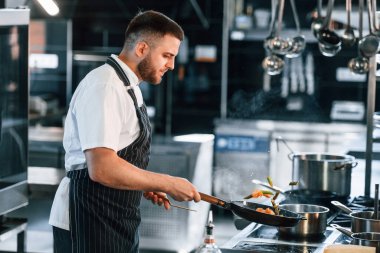 Kızartma tavasında alevler. Şef mutfakta yemek hazırlıyor..