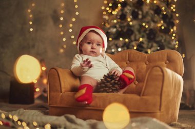 Küçük şirin kanepede. Bebek evde kaldı. Yeni yıl süslemeleri. Tatil kavramı.