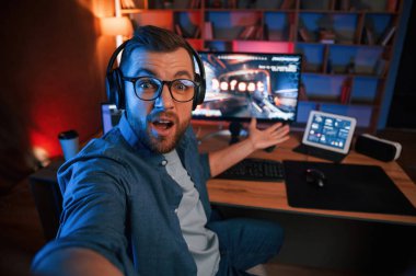 Adam bilgisayarında nişancı oyunu oynuyor. Neon ışıkları.