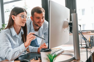 Bilgisayar kullanarak. İki genç tasarımcı ofiste birlikte çalışıyor..