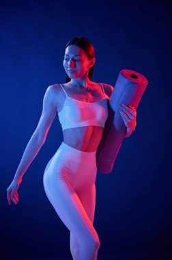 Ön manzara. Paspası tutuyorum. Spor elbiseli genç bayan stüdyoda neon ışıklarıyla bekliyor..