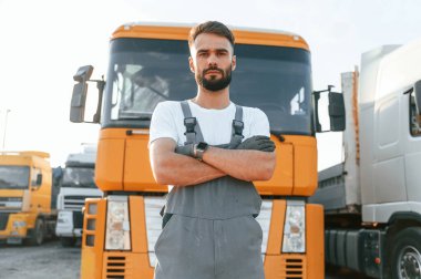 Durup kameraya poz vermek. Üniformalı bir adam büyük bir kamyon için hizmet veriyor..