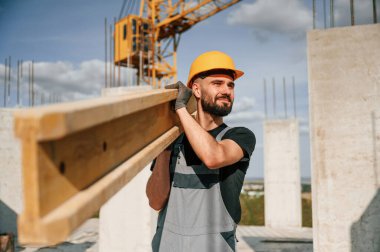Tahta bir kalasla tutuyor ve yürüyordu. Üniformalı adam inşaat alanında çalışıyor..