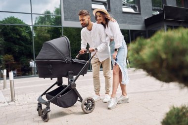Aşk kavramı. Genç ebeveynler dışarıda bebek arabasıyla geziyorlar..