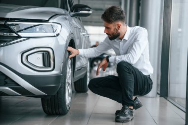 Lastikleri kontrol ediyorum. Beyaz elbiseli genç adam araba galerisinde..