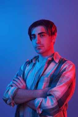 Arms crossed. Man standing in the studio with neon light.