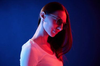 Durup poz vermek. İçerideki neon ışıkta duran genç bir kadının portresi..