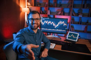 Hisse senedi tüccarı kapalı alanda bilgisayar başında çalışıyor. Değişim ve para kavramı.