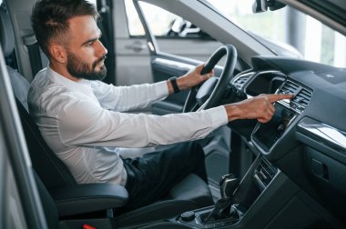 Yan görüş. Bir otomobilin içinde oturuyor. Beyaz elbiseli genç adam araba galerisinde..