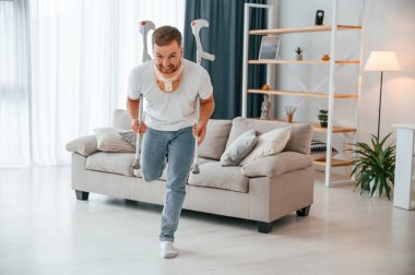 Koltuk değnekleriyle oynamak, kayak taklidi yapmak, görüntü. Evdeki adam içeride. Yaralı..