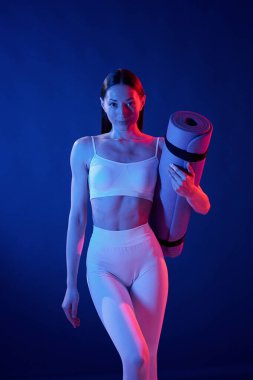 Ön manzara. Paspası tutuyorum. Spor elbiseli genç bayan stüdyoda neon ışıklarıyla bekliyor..