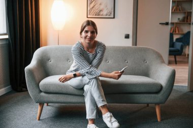 Genç bayan dairedeki kanepede oturuyor..