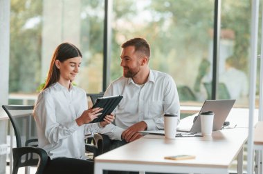 Fikirlerimizi paylaşıyoruz. Erkek ve kadın modern ofiste birlikte çalışıyorlar..