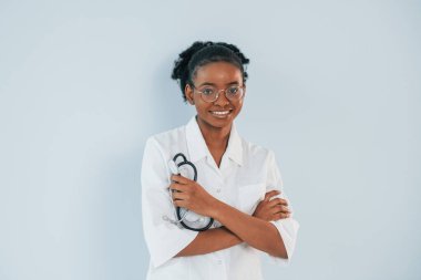Steteskopla duruyorum. Genç Afrikalı Amerikalı kadın beyaz arka plana karşı..