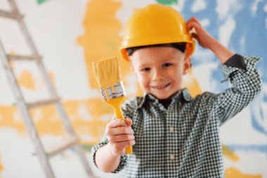 Arkasında mavi ve sarı renkler var. Ukrayna ve barış kavramı. Küçük çocuk ev odasında duvarları boyuyor..