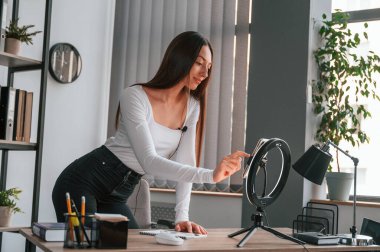 Akıllı telefonu kayıt için kuruyorum. Beyaz elbiseli genç ve güzel bayan ofiste..