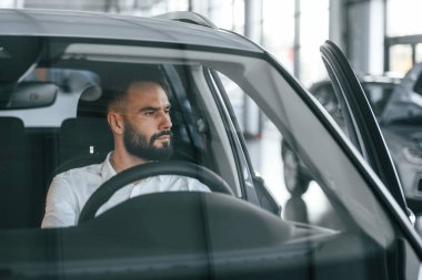 Otomobilin içinde. Beyaz elbiseli genç adam araba galerisinde..