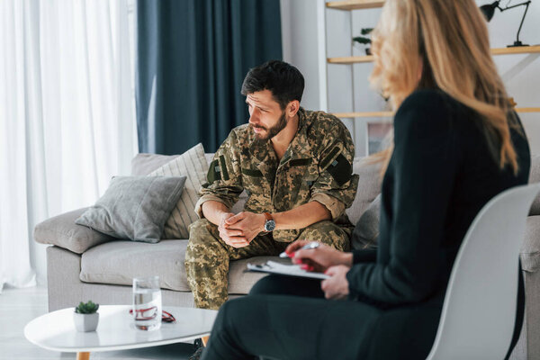 Soldier have therapy session with psychologist indoors.