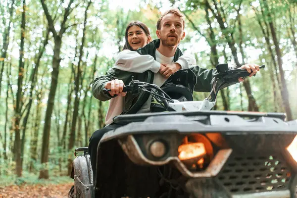 stock image Man is handling the transport. Young couple riding a quad bike in the forest.