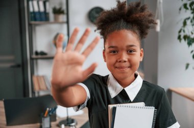 Çak bir beşlik. Okul üniformalı şirin küçük kız içeride, ev odasında dikiliyor..