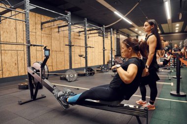 Yan görüş. Spor salonunda kürek çeken sporcu bir kadın..