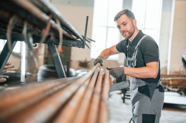 Metal parçalarının uzunluğunu ölçüyorum. Üniformalı adam iş yerinde tarım tekniğinin detaylarını geliştiriyor..