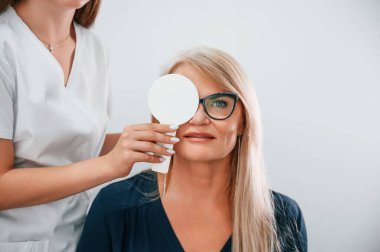Gözü kapatıyorum. Kadının görüşü özel bir cihaz kullanan klinik çalışanı tarafından test ediliyor..
