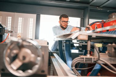 Çarşaf kesme makinesi. İşletim cihazı. Beyaz elbiseli matbaacı içeride..