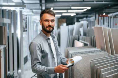 Elinde not defteriyle dikiliyorsun. Tarz sahibi güzel adam ev için malzeme deposunda..