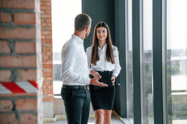 Büyük panoramik pencerelerin yanında. Gündüz vakti sanayi işçileri binada. İnşaat konumu.