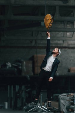 Vinç kancasına asılıydı. Fabrikada resmi siyah giyim müdürü..