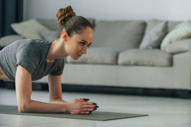 Omurga egzersizleri. İnce vücutlu ve yoga elbiseli genç bir kadın evde..