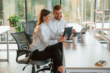 Gülümsüyor ve konuşuyor. Erkek ve kadın modern ofiste birlikte çalışıyorlar..