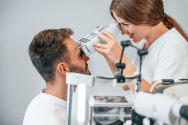 Modern teknolojiler. Özel optometrist cihaz kullanarak klinikteki kadın doktor tarafından erkeğin görüşü kontrol edildi..