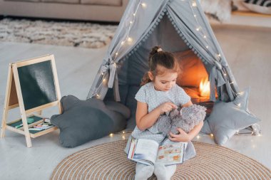 Gündüz vakti. Evdeki çadırda oynayan sevimli küçük kız..