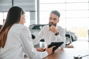 Bir anlaşma yapıyorum. Masanın yanında oturuyor. Beyaz elbiseli bir adam araba galerisinde birlikte..