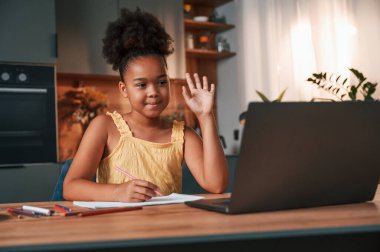 Çevrimiçi çalışma. Gündüz vakti evde rahat giyinen sevimli siyah kız var..