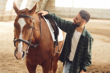 Eyeri kuruyorum. Atlı genç adam hangarda..