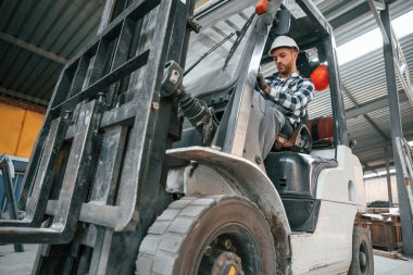 Forkliftin içinde. Üniformalı fabrika çalışanı içeride..