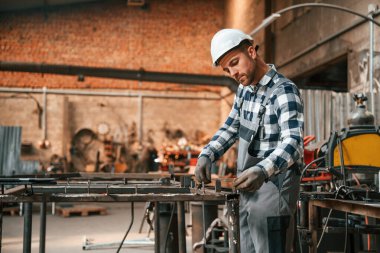 Tamirci fabrika makinesiyle çalışıyor. Üniformalı depo çalışanı içeride..