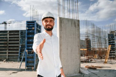 Mühendis elini uzatıyor. Üniformalı adam inşaat alanında çalışıyor..