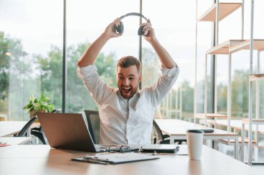 Başarıyı kutluyoruz. Resmi giyinmiş mutlu adam modern ofiste çalışıyor..