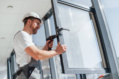 Yeni pencereler takılıyor. Modern odada kapalı alanda çalışan tamircinin yakın görüntüsü..