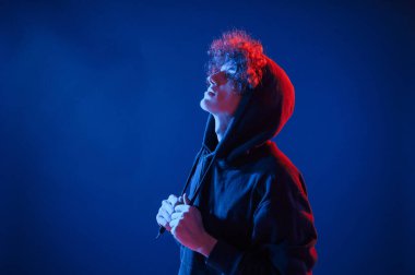 Yan taraftaki manzarayı kapat. Kıvırcık saçlı genç adam kapalı alanda neon ışıkla aydınlatılır..