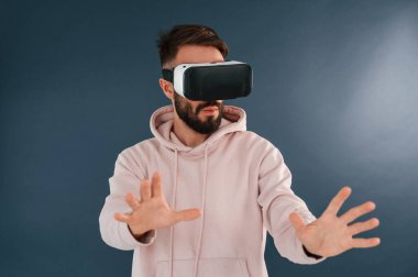 VR gözlüklü. Yakışıklı adam stüdyoda mavi arka planda..