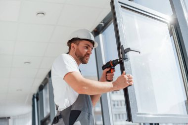 Gri üniformalı. Tamirci modern odada kapalı alanda çalışıyor..